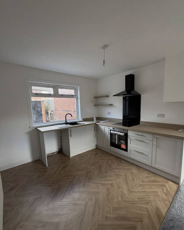 Newly fitted kitchen with pale units and herringbone flooring